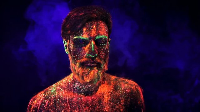 Portrait of a bearded man in ultraviolet light in smoke