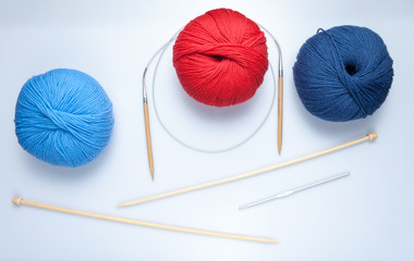 top view of colored yarn balls and knitting needles on white