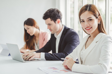 Fototapeta premium Portrait young beautiful asian business woman in formal suit in office working with team at desk during meeting