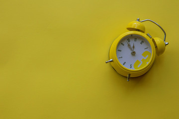 Cute small yellow  ring clock on bright yellow  background 
