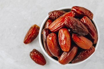 Dried dates in white bowl on grey background