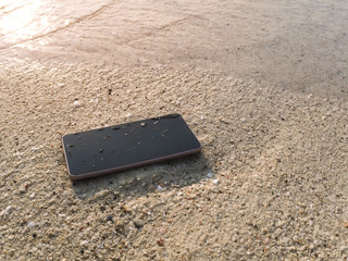 Mobile smart phone on the sandy beach with soft waves of sea background.  Internet of thing concept.