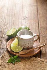 Cup of Warm Hot Lemon Drink with lemon slice on wooden background