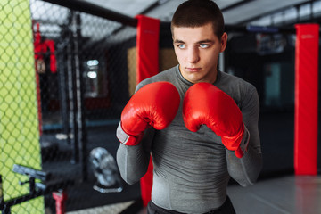 Male boxer engaged in training in the gym, in a cage for a fight without rules, Boxing coach
