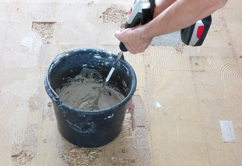 Man is mixing grey concrete and prime in the bucket.