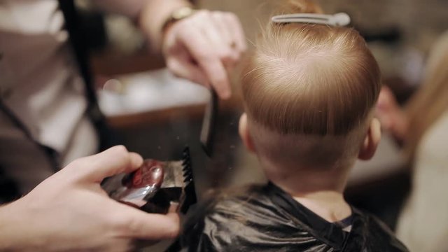 A small child is being prepared for a haircut in a hairdresser