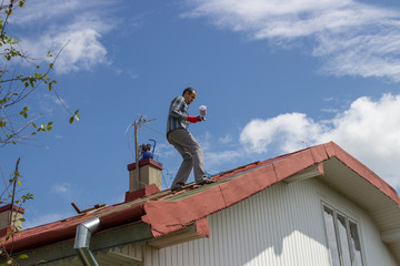 The man stands on the roof to paint