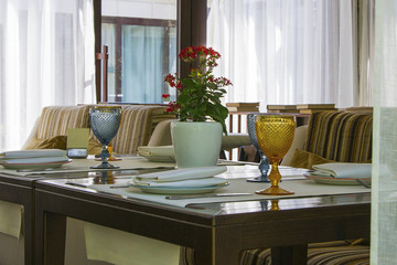 Modern european restaurant with wooden table and multi-colored sofa close to window.Table setting.