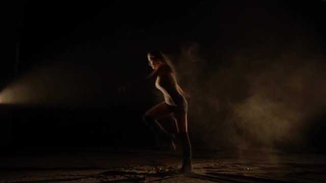 Graceful woman in the sand dancing jumping, slow motion