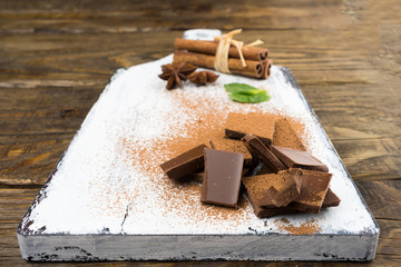 Pieces of chocolate, cinnamon, mint and star anise on a cutting Board.