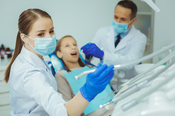 Look at this. Worried teenager keeping mouth opened while visiting dentist cabinet