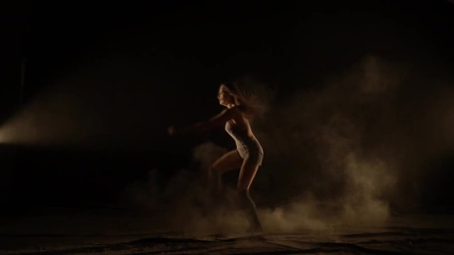 Slow-motion shooting, a woman in gaiters dancing throwing dust, jumping in the studio