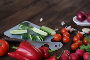 Fresh vegetables sliced for a salad on a cutting board, on an old wooden table