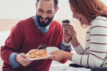Tasty lunch. Emotional young cheerful couple laughing while looking at the tasty cakes on their...