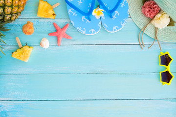 Holidays concept. Pineapple slices, shells, starfish, slippers, straw hat and sunglasses on wood plank blue color. Summer vacation background concept. top view