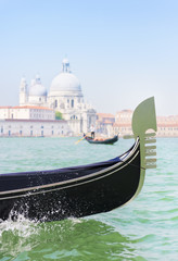 Fototapeta na wymiar Traditional venetian gondola and gondolier with tourists between Grand Canal and Giudecca Canal of Venice city against basilica Santa Maria della Salute background. Italy.