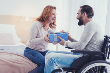 Big present. Cheerful positive young woman smiling and giving a wonderful present to her optimistic...