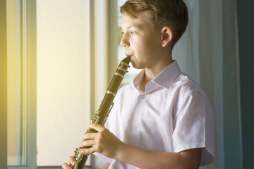 The boy learns to play the clarinet and looks out the window. Musicology, music education and...