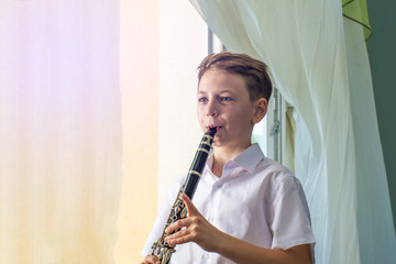 The boy learns to play the clarinet at the window. Musicology, music education and education.
