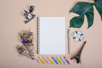 Flat lay empty book and pen, clip, dry flower and green leaf for design work on yellow pastel color background.