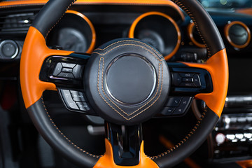 Orange black steering wheel in the car.