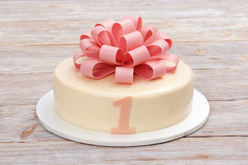 Cake with chocolate bow on wooden background.