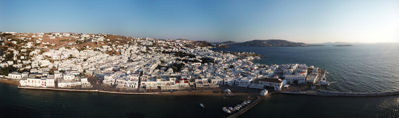 Naklejka premium Aerial ultra wide panoramic drone view of iconic chora of Mykonos island featuring picturesque little Venice and church of Paraportiani at sunset, Cyclades, Aegean, Greece