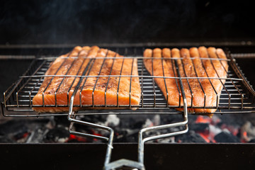 Salmon steak preparing on a barbecue grill over charcoal. Outdoor.