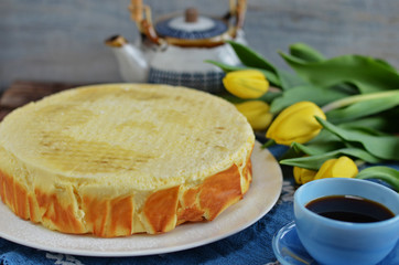 Healthy round cheesecake on a white plate. Coffee in a blue cup