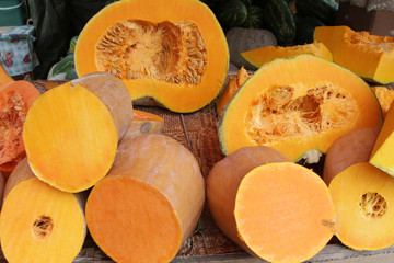 Pumpkins on open market, pieces of pumpkin, pumpkin pile. Big orange pumpkins for Halloween holiday. fresh organic squashes for holiday. Pumpkin background. Vegetables and fruit texture. Healthy food.