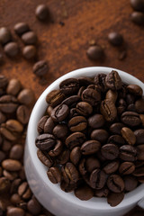  Photo closeup of coffee beans in white cup. Rusty background. Copy space.