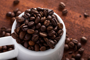  Photo closeup of coffee beans in white cup. Rusty background. Copy space.