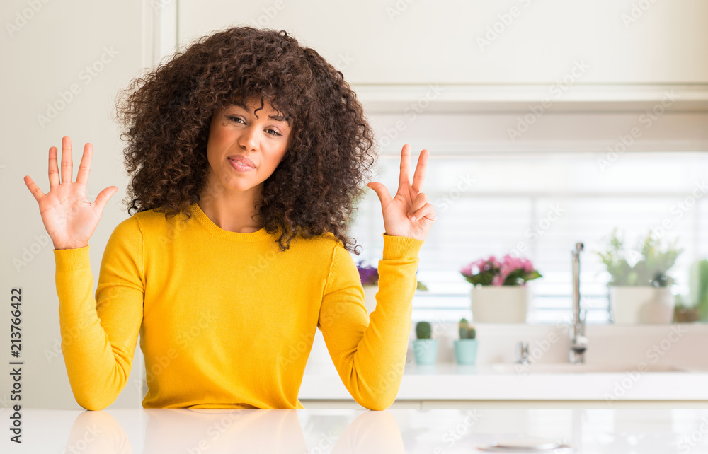 Poster African american woman wearing yellow sweater at kitchen showing and pointing up with fingers number eight while smiling confident and happy.