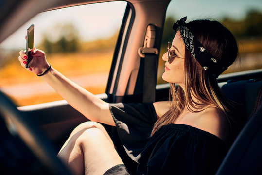 Boho girl in vintage van taking road trip selfie