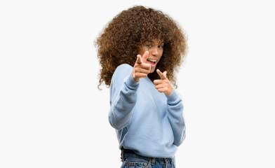 African american woman wearing a sweater pointing fingers to camera with happy and funny face. Good energy and vibes.