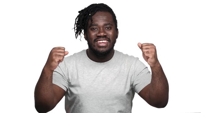 Portrait of delighted afro man with stylish hairdo and mustache clenching fists and screaming in triumph, isolated over white background slow motion. Concept of emotions