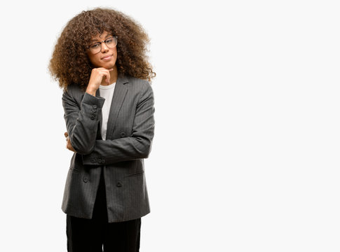 African american business woman wearing glasses with hand on chin thinking about question, pensive expression. Smiling with thoughtful face. Doubt concept.