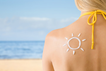 Sun shape created from sunscreen lotion on young woman's back. Skin protection. Hot day. Safety...