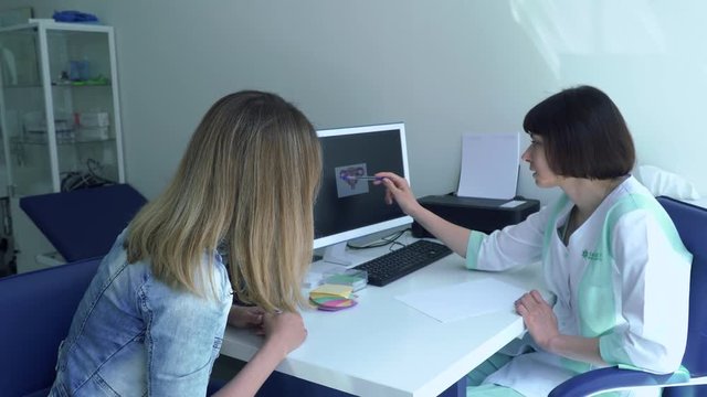 Gynecologist explain patient how work her womb showing the picture on computer