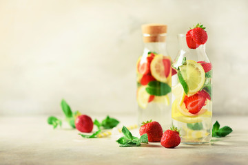 Strawberry detox water with mint, lemon on grey background. Citrus lemonade. Summer fruit infused water. Copy space