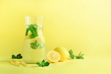 Detox water with mint, lemon on yellow background. Banner with copy space, sunlight bokeh. Citrus lemonade. Summer fruit infused water.