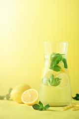 Detox water with mint, lemon on yellow background. Banner with copy space, sunlight bokeh. Citrus lemonade. Summer fruit infused water.