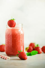 Bottle with vegan strawberry smoothie on grey background with copy space. Summer food and clean eating concept, vegan diet. Pink detox beverage with fresh berries