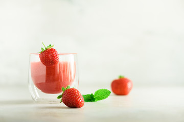 Red strawberry milkshake in glass on grey background with copy space. Summer food concept, vegan...