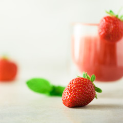 Glass with vegan strawberry smoothie on grey background with copy space. Square crop. Summer food and clean eating concept, vegan diet. Pink detox beverage with fresh berries