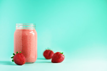 tasty fruit and berries smoothie milkshake in a cute bottle on a blue background with berries around for happy morning