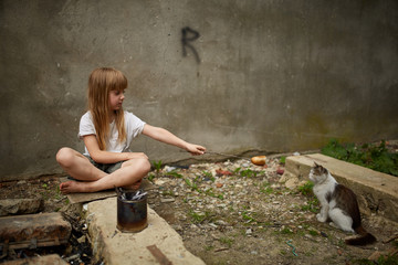Generous homeless girl sharing bread with stray cat, selective focus.
