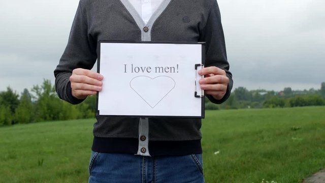 A man holding a sign with the inscription I love men, close-up, homosexuality