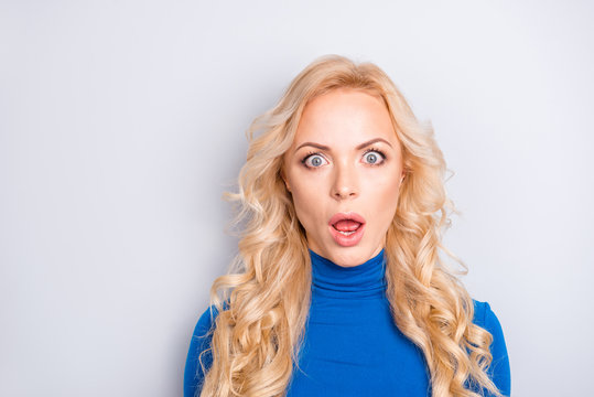 Portrait of sexy, scared, impressed, shocked, stylish, pretty, cute, charming, nice, blonde woman in blue turtleneck  with wide open eyes and mouth looking at camera