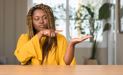 African american woman at home very happy pointing with hand and finger